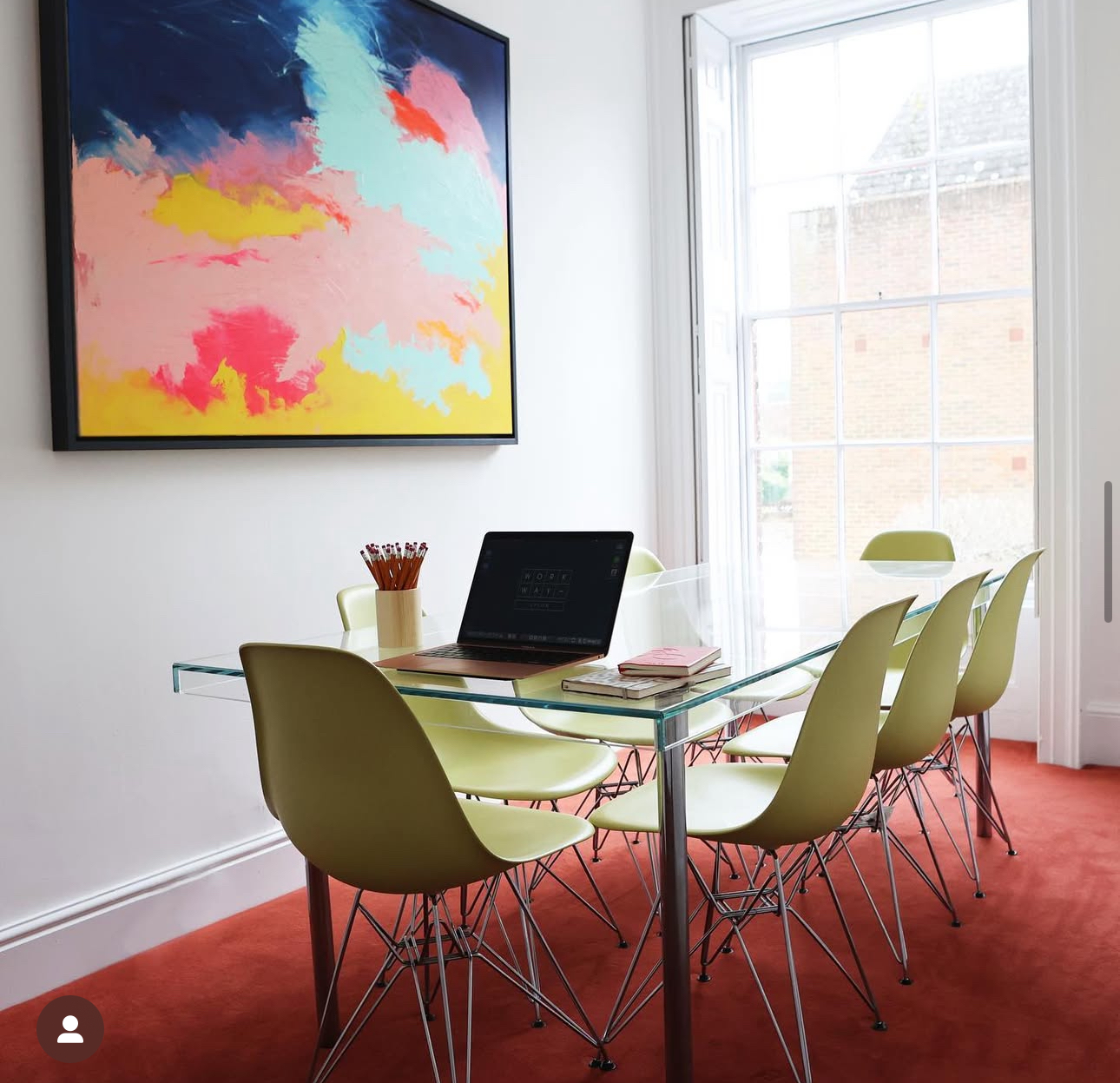 Bright meeting room with glass table and colorful artwork